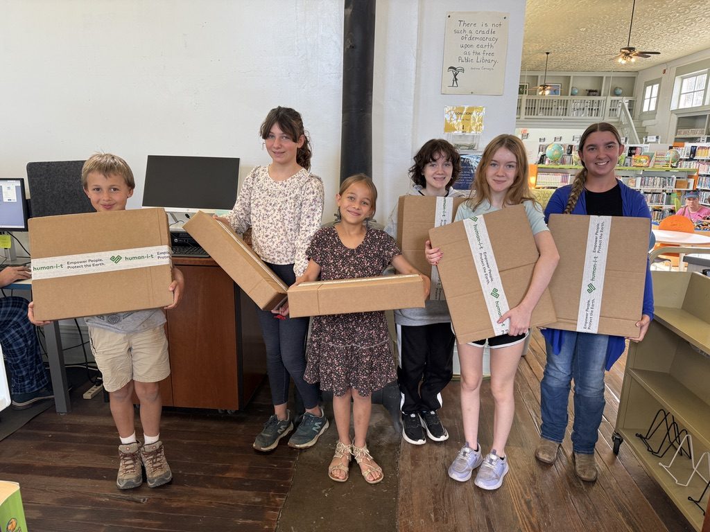 Six students at the Jeff Davis County Library holding boxes containing their new laptops